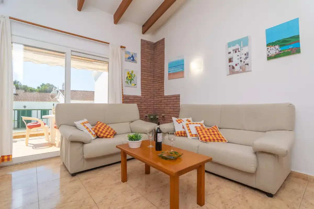 A living room with seating, a coffee table, and sliding glass doors opening onto a balcony.