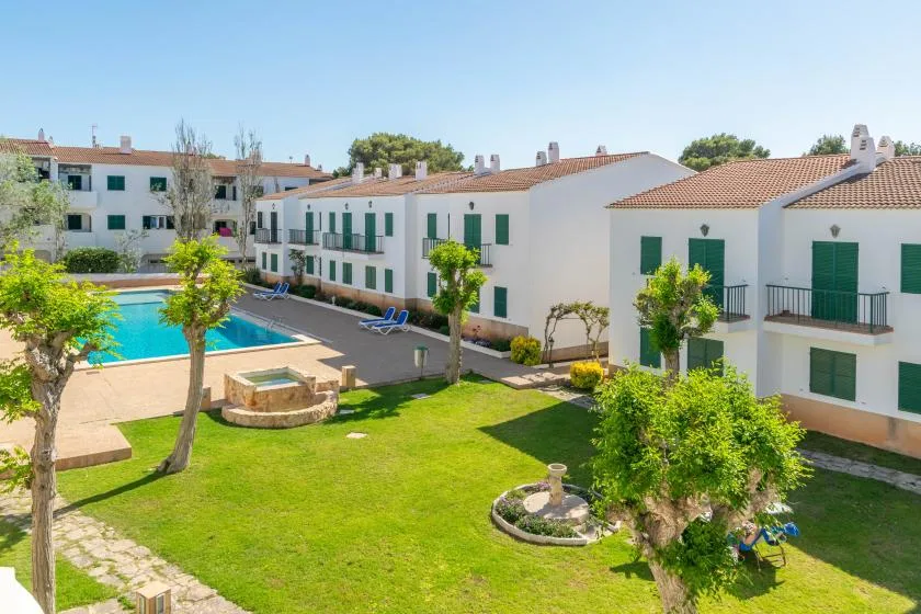 A landscaped courtyard with a swimming pool and white residential buildings.
