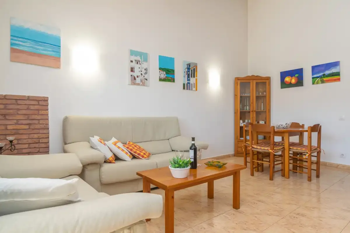 A living and dining area with light-colored seating and a wooden table.