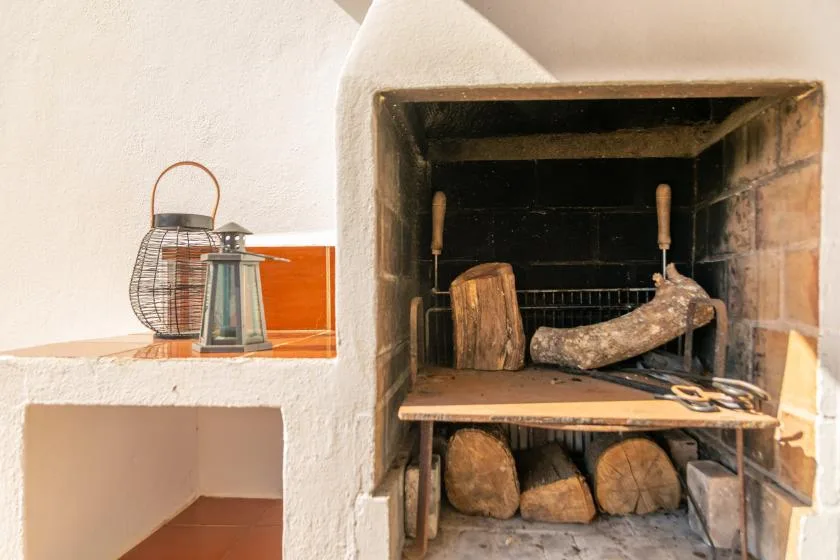 A built-in fireplace with firewood stacked beneath the hearth and lanterns on the ledge.
