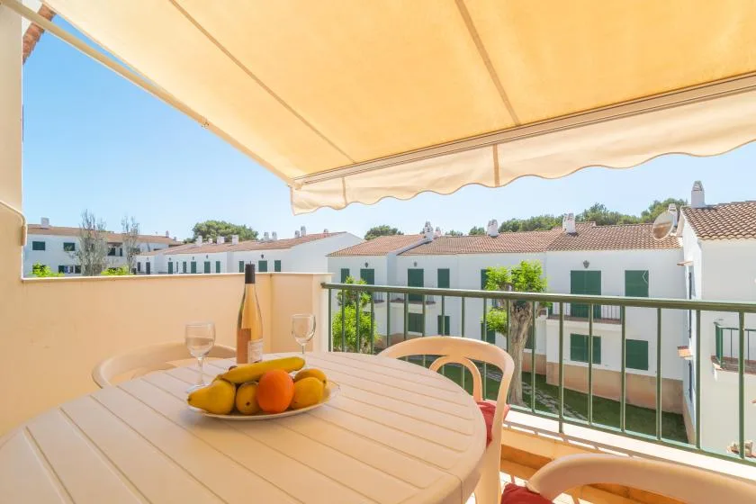 A balcony dining area with a table beneath a retractable awning.