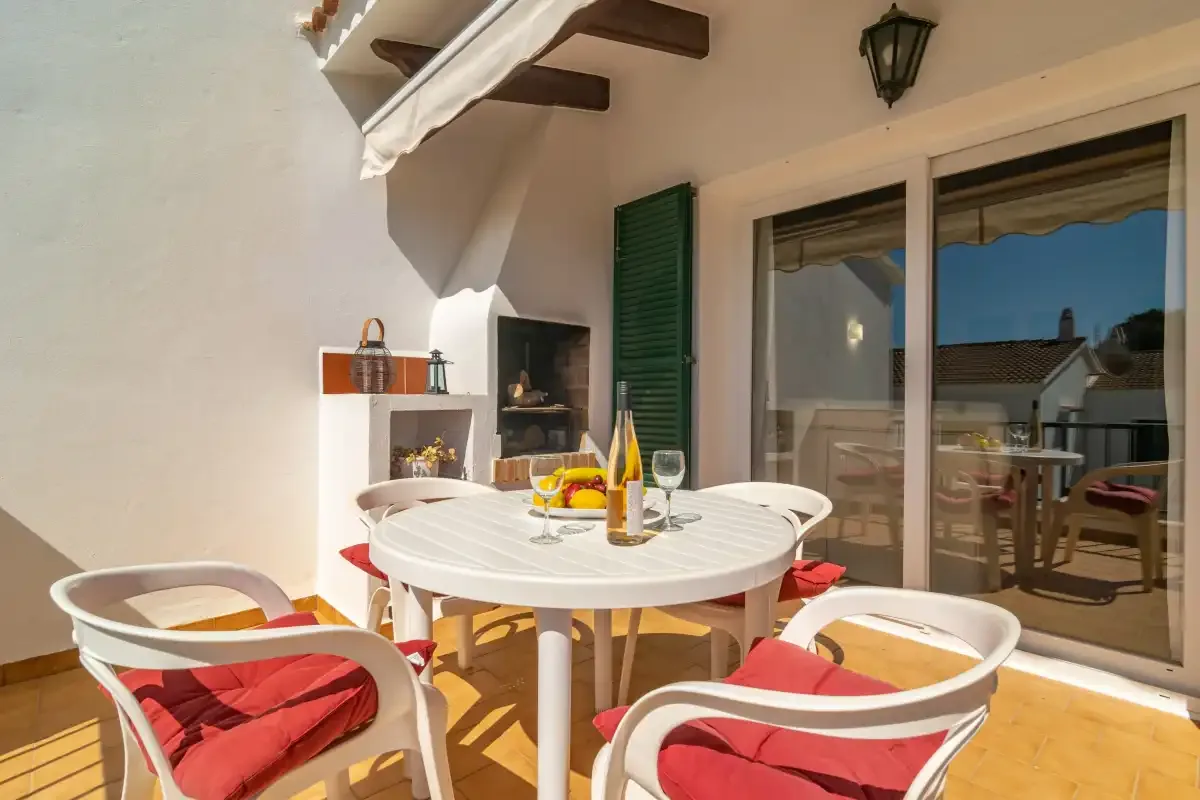A sunny patio dining area with a round table and cushioned seating.