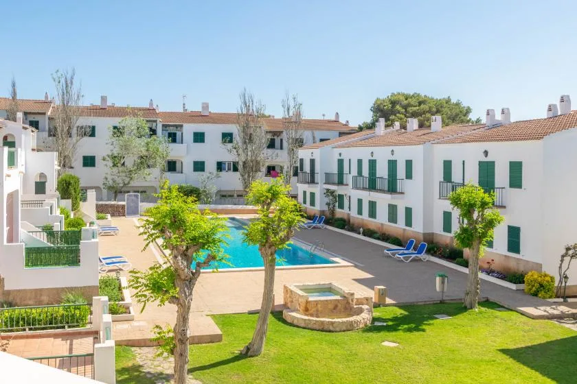 Residential courtyard with a swimming pool, paved walkways, and surrounding greenery.