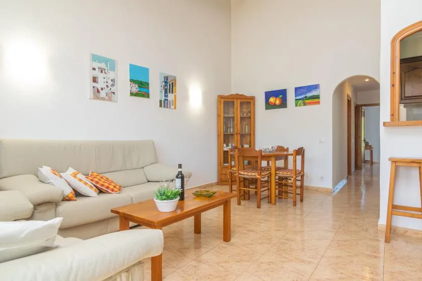 A bright living and dining room with seating, a wooden table, and wall art.