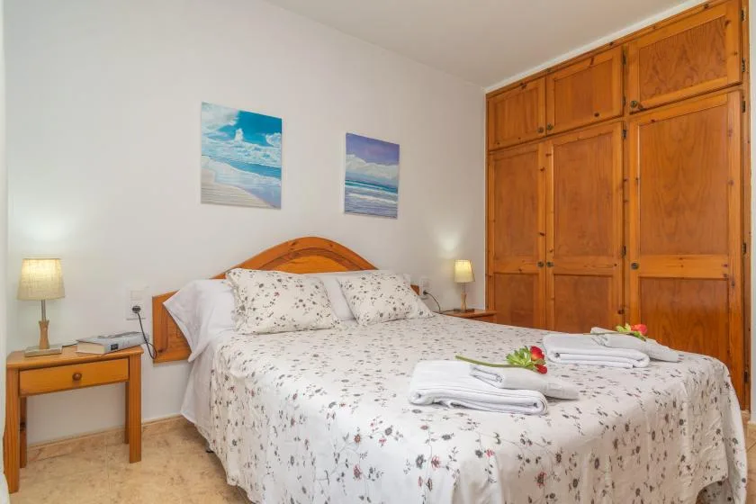 A bedroom with a double bed, floral bedding, and a large wooden wardrobe.