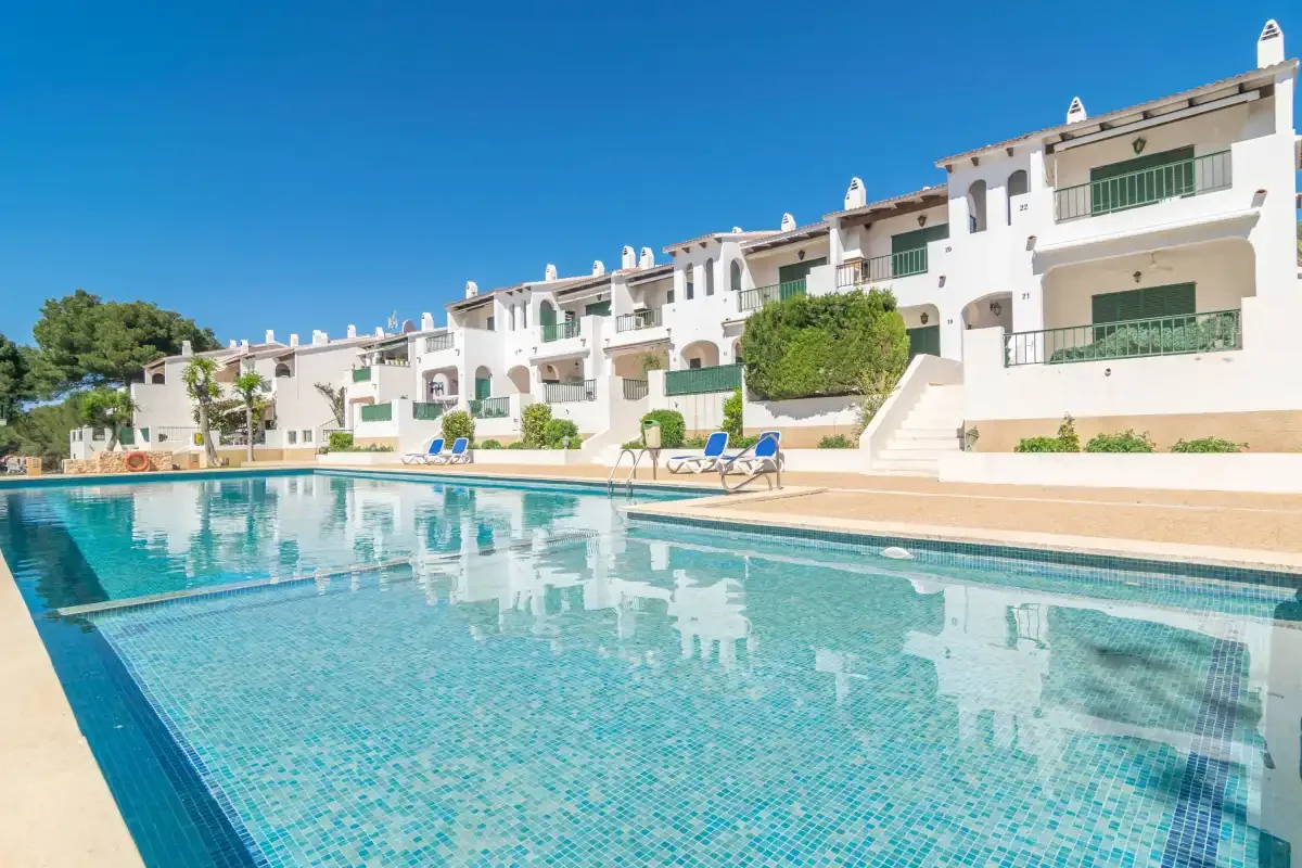 A swimming pool in front of white buildings with balconies.