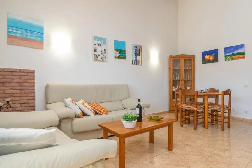 A bright living room with seating, a wooden coffee table, and a dining area.
