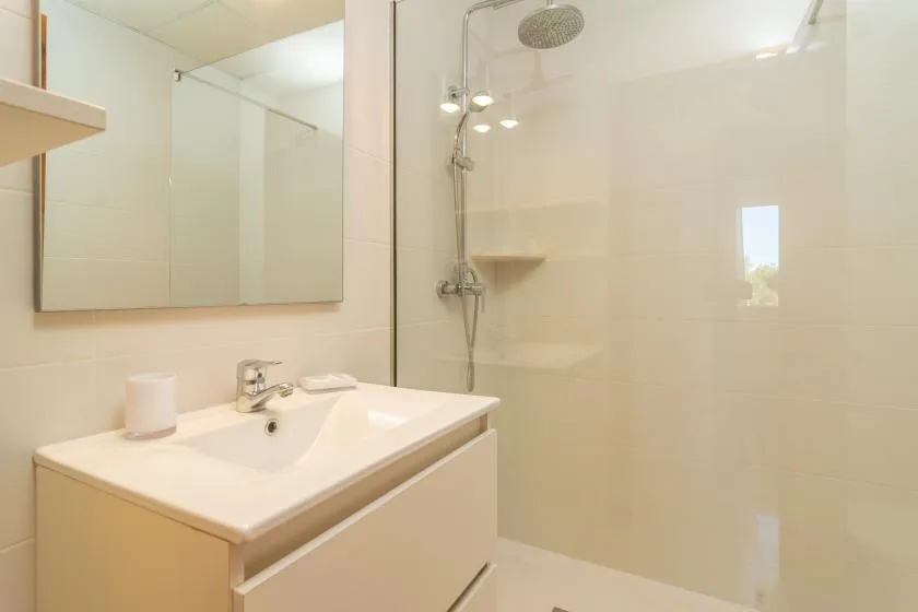 A bright bathroom with a sink and a glass-enclosed shower.
