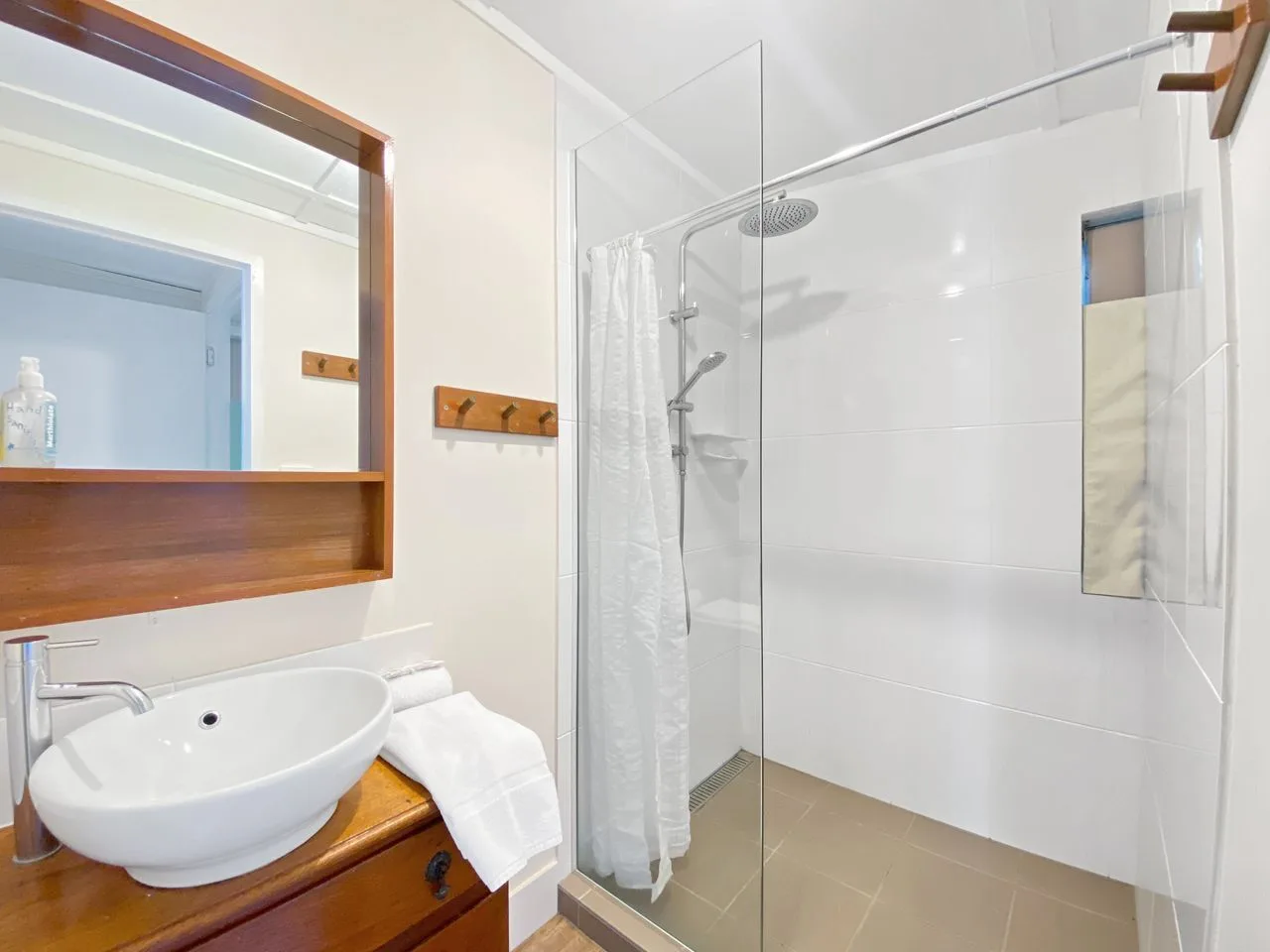 Un baño luminoso con lavabo y ducha de vidrio.