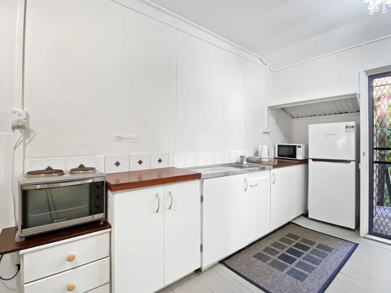 Una cocina luminosa con gabinetes blancos, una encimera y electrodomésticos.