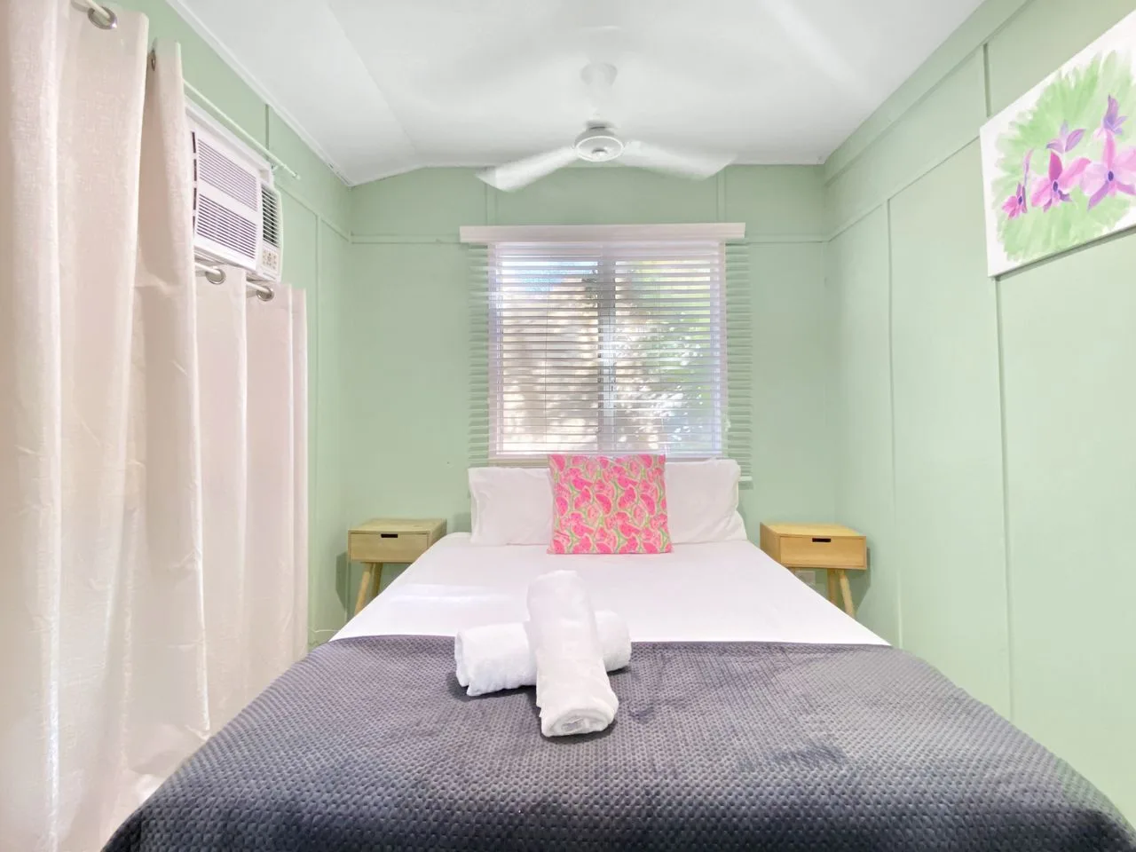 Dormitorio con una cama bien hecha debajo de una ventana.