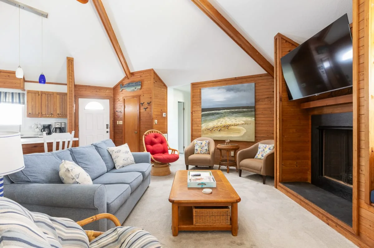A wood-paneled living room with seating around a coffee table and a large window.