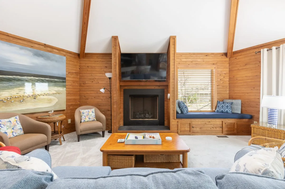 A bright living room with a fireplace, seating, and a wooden coffee table.