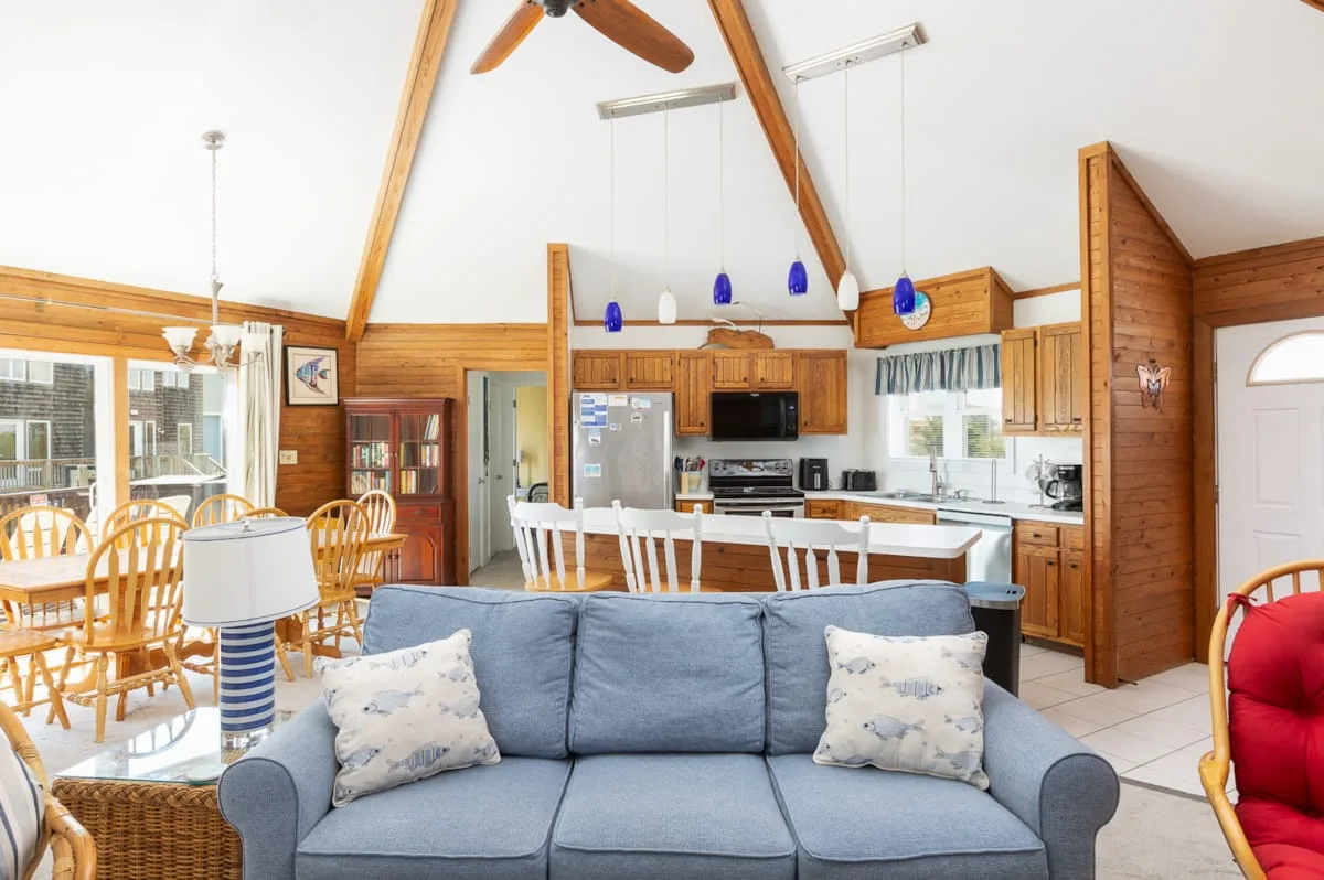 A wood-paneled living and dining area with a blue sofa and open kitchen.