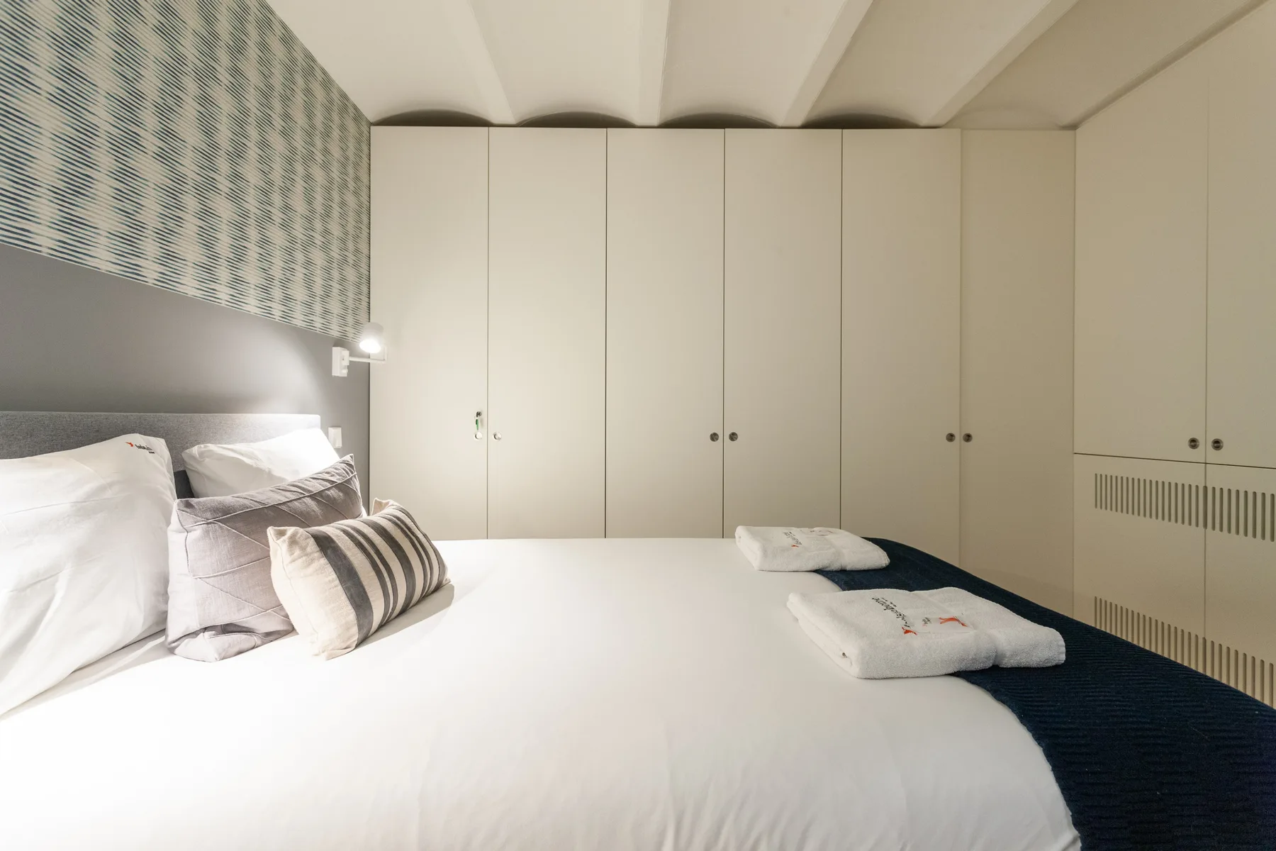Un dormitorio con una cama y armarios empotrados junto a la pared.