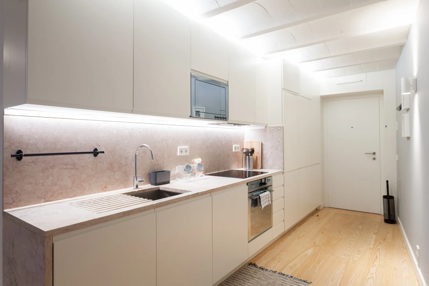 Una cocina moderna y luminosa con una encimera larga y electrodomésticos integrados.