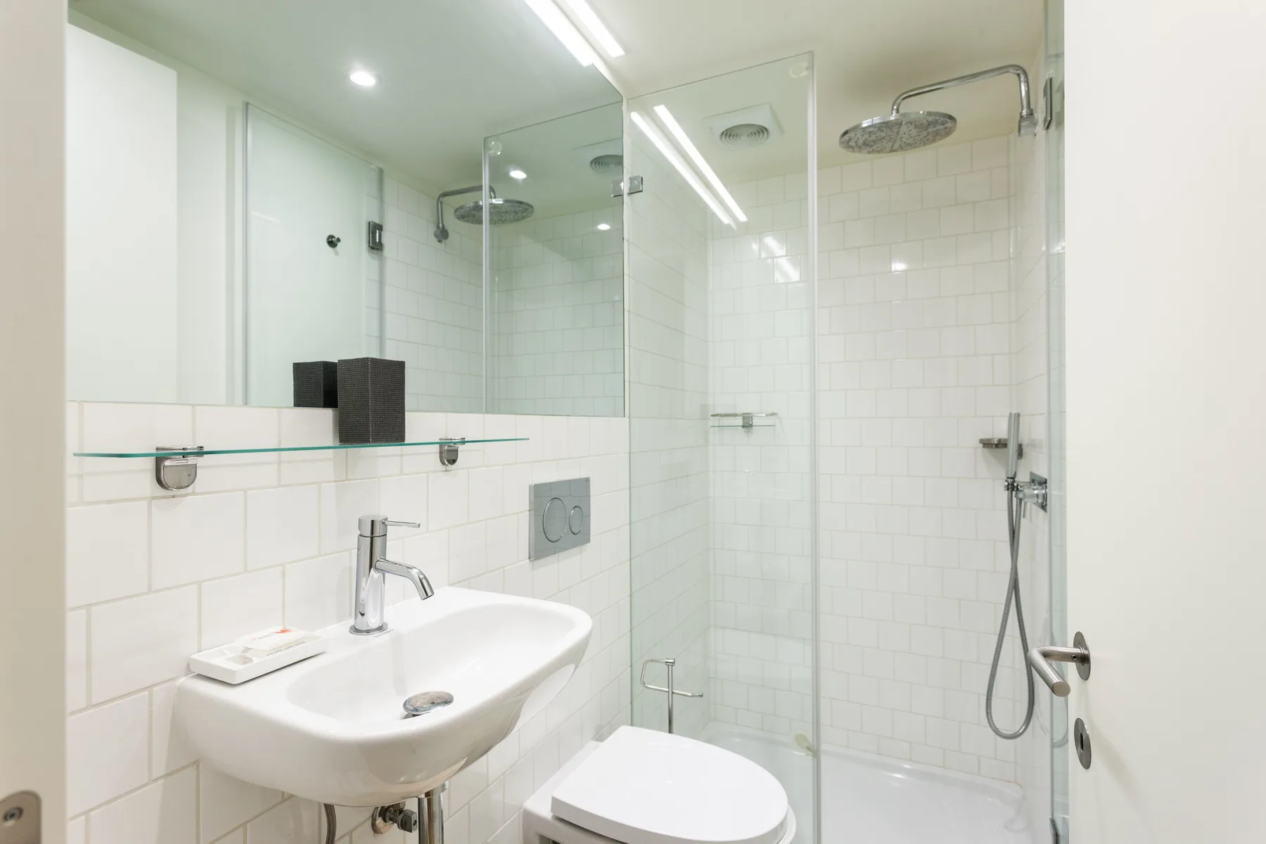 Un baño luminoso con lavabo y ducha de mampara de vidrio.