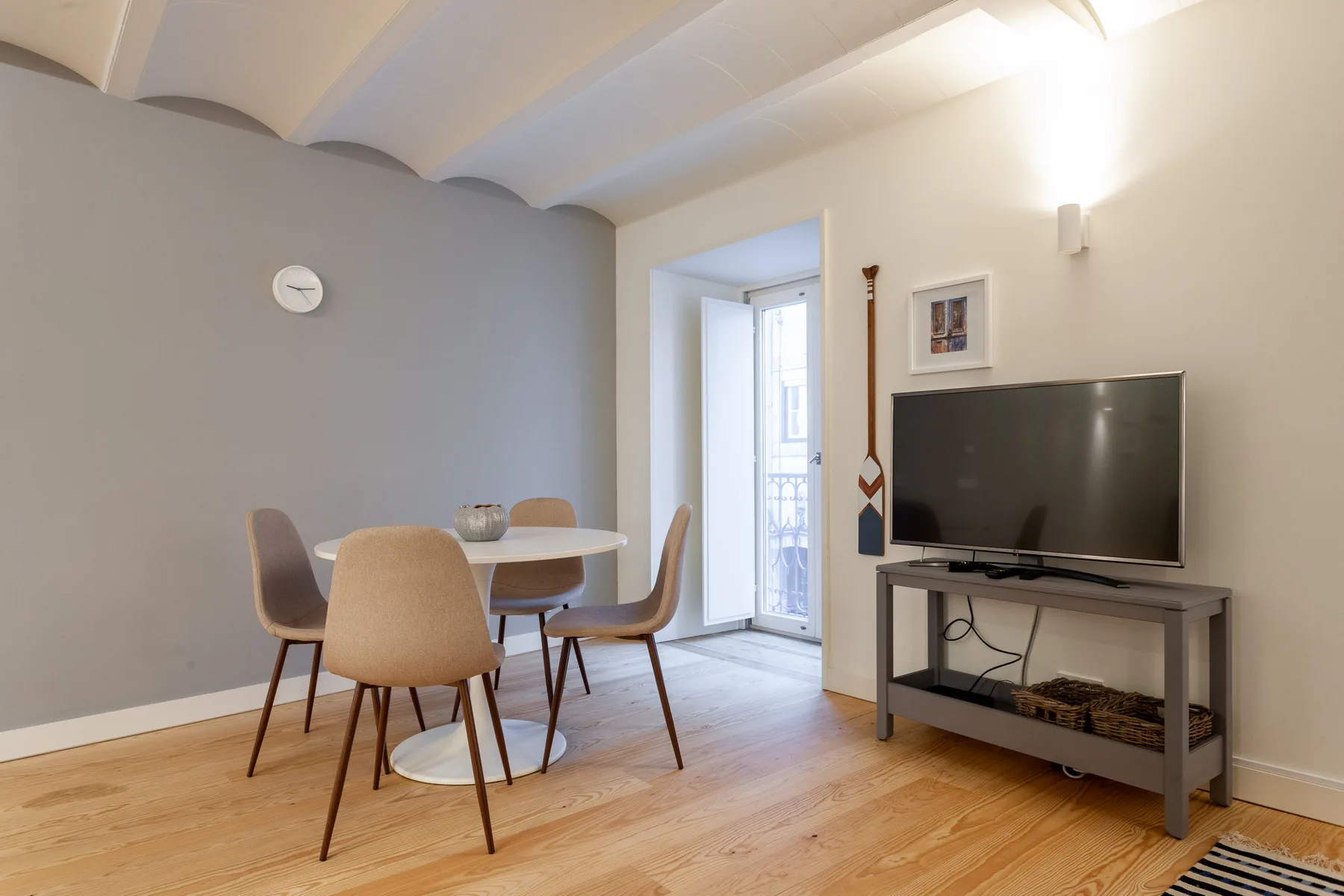 Una sala de estar y comedor con un televisor y una mesa redonda.