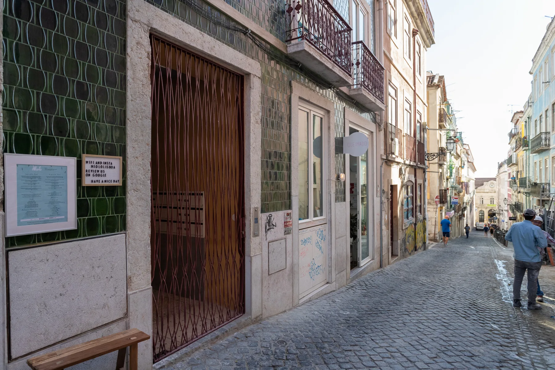 Una calle estrecha de adoquines bordeada de edificios altos y comercios.