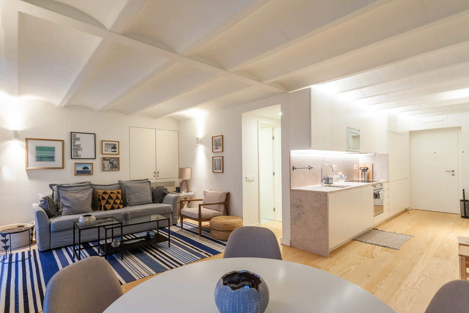 Sala de estar y comedor con asientos, una alfombra y cocina abierta.