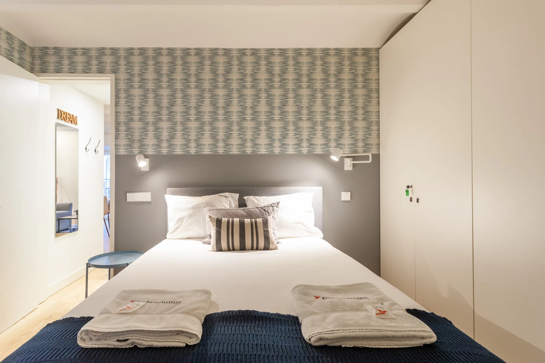 Un dormitorio con una cama bien tendida y un revestimiento de pared estampado.