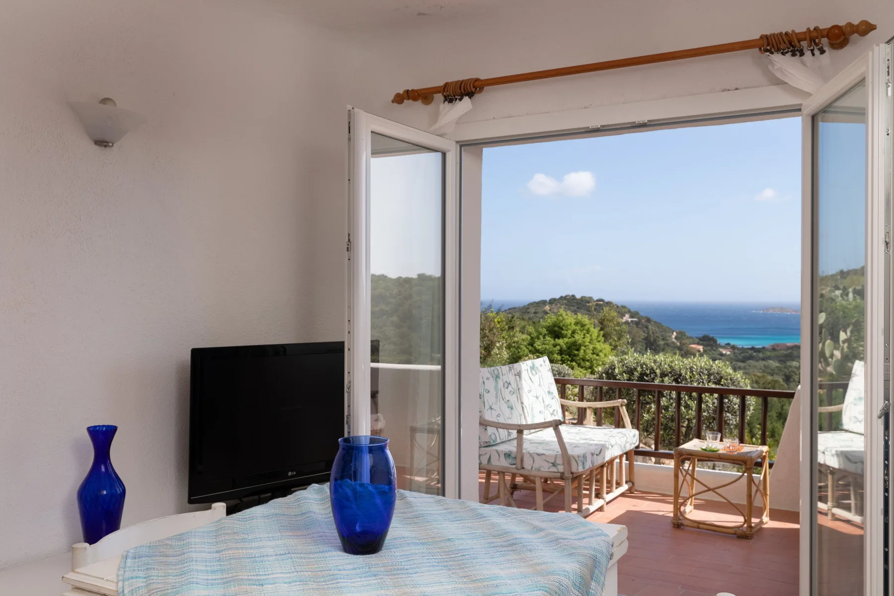 Un dormitorio se abre a un balcón con asientos y vistas a la costa.