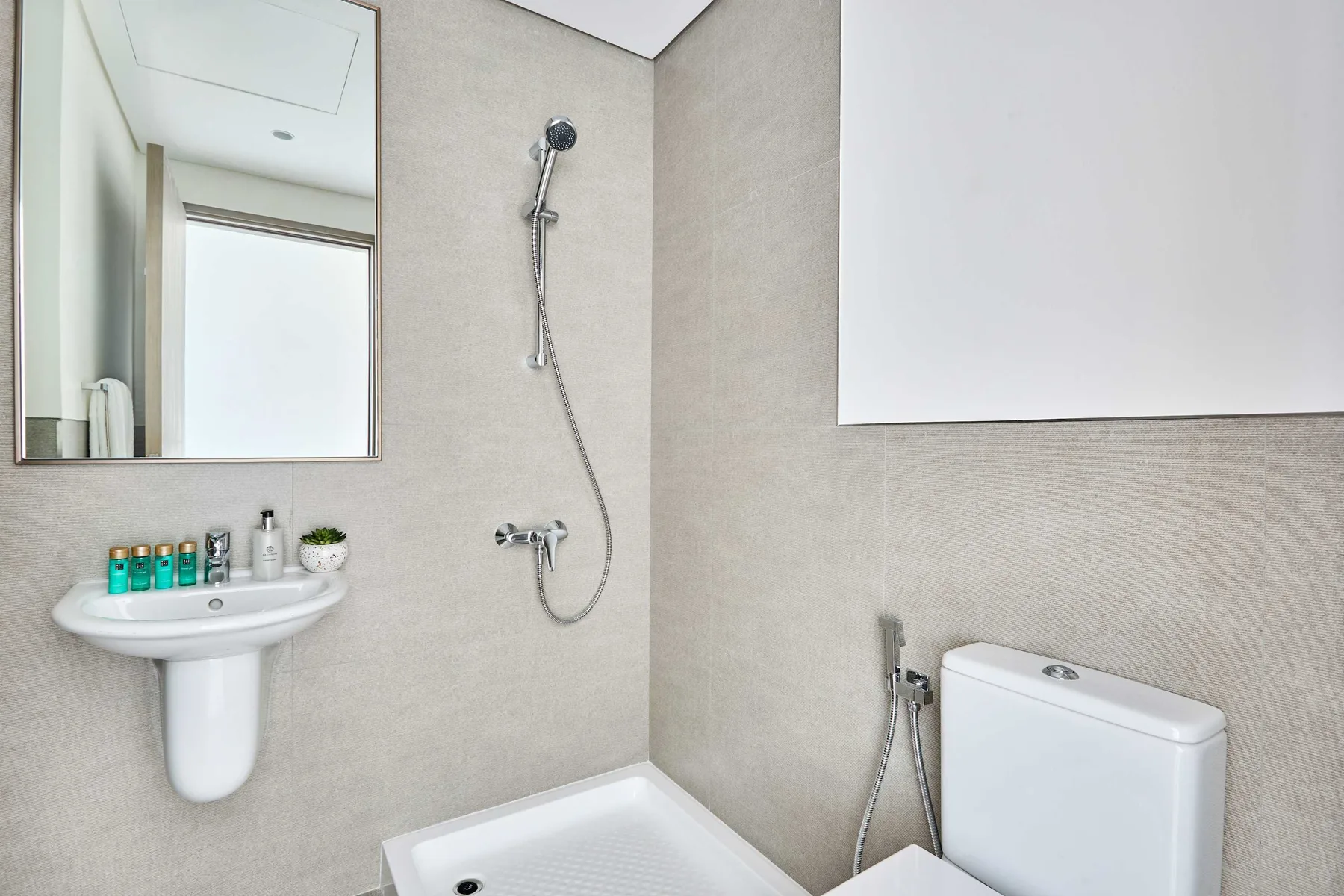 Un baño luminoso con lavabo de pedestal, espejo de pared y ducha.