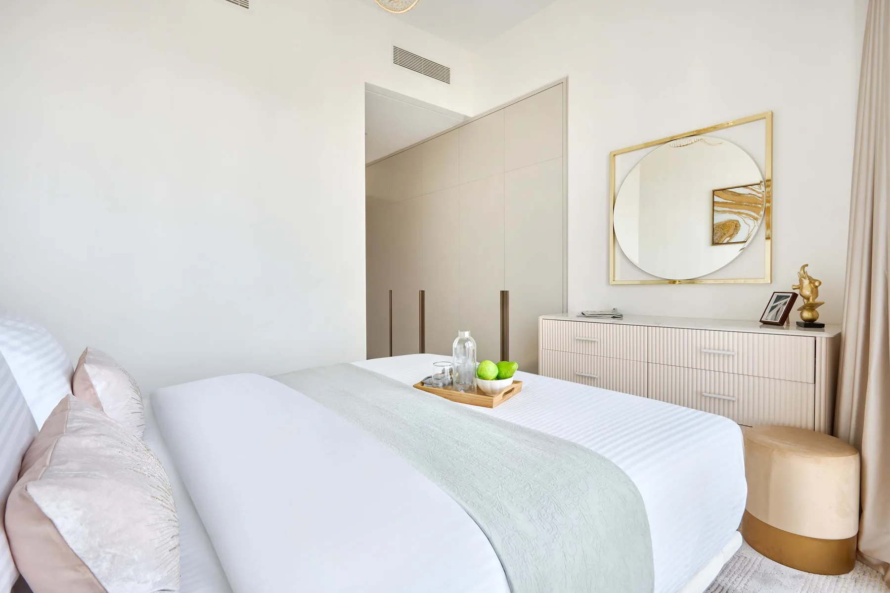 Un dormitorio con una cama bien arreglada, una cómoda y un espejo en la pared.