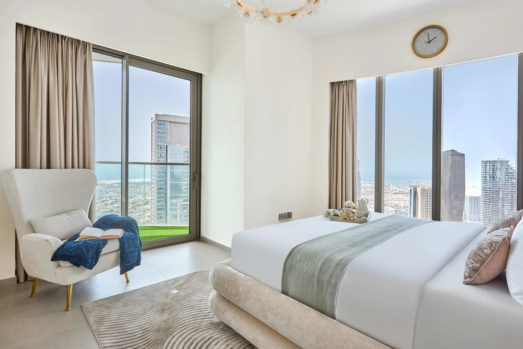 Un dormitorio luminoso con una cama grande junto a ventanales con vistas a la ciudad.
