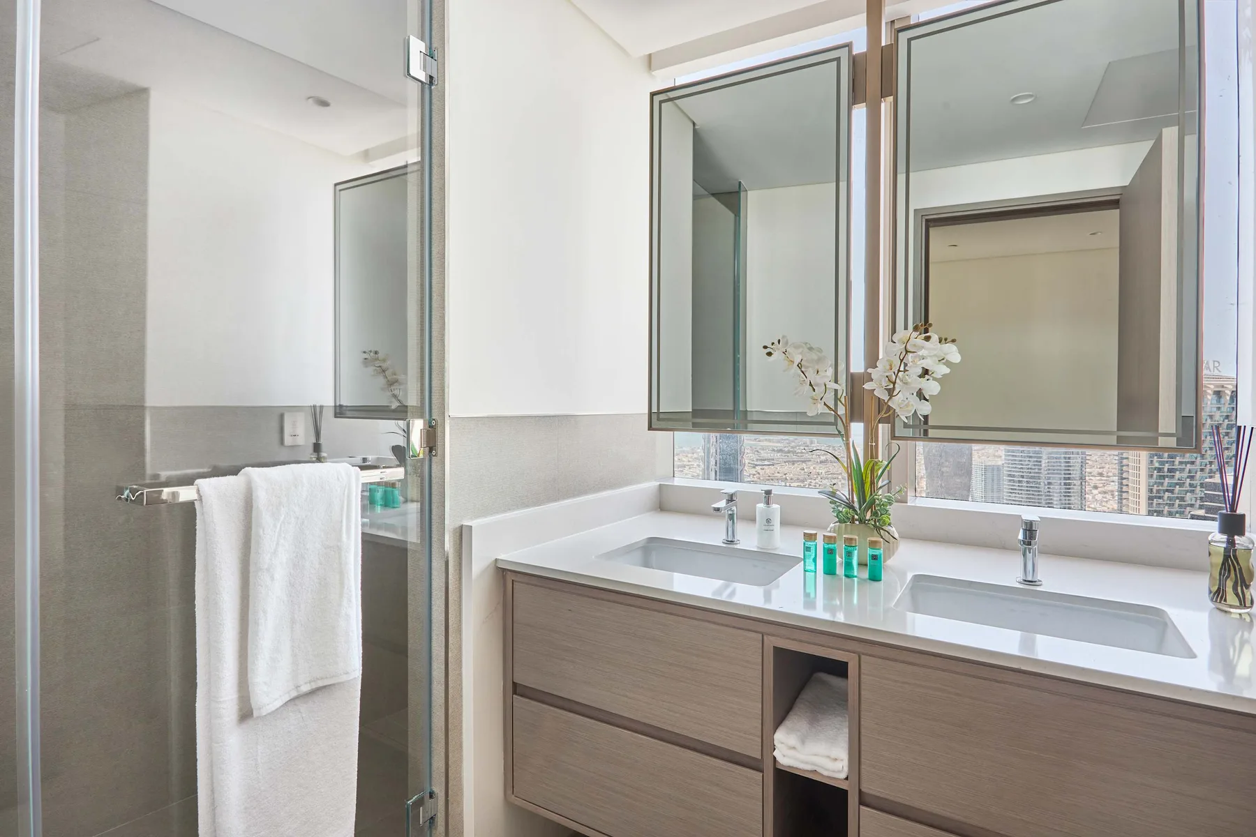 Un baño luminoso con un mueble largo, dos lavabos y espejos grandes.