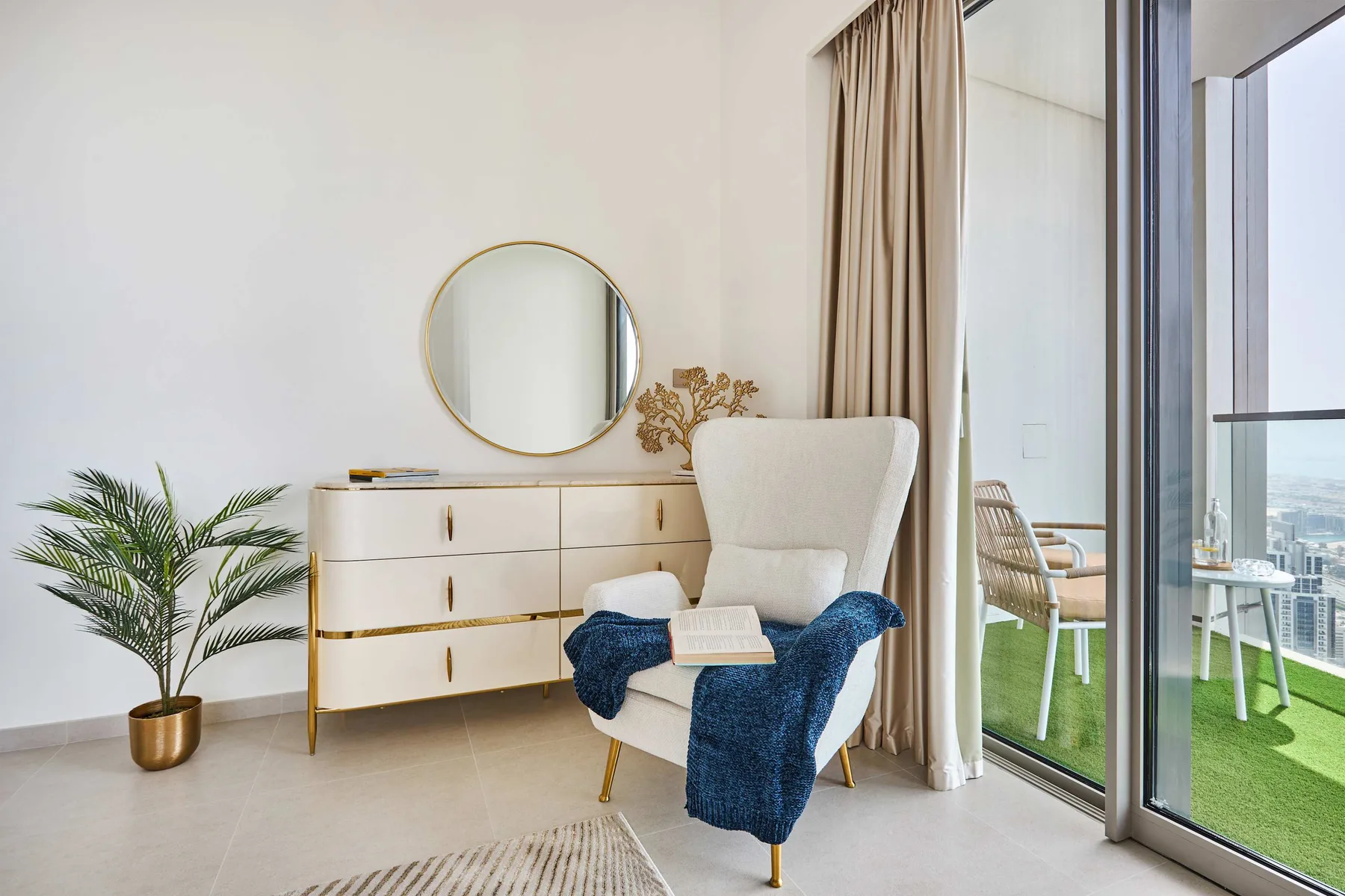 Una luminosa zona de estar cuenta con un sillón junto a una cómoda y puertas de vidrio.