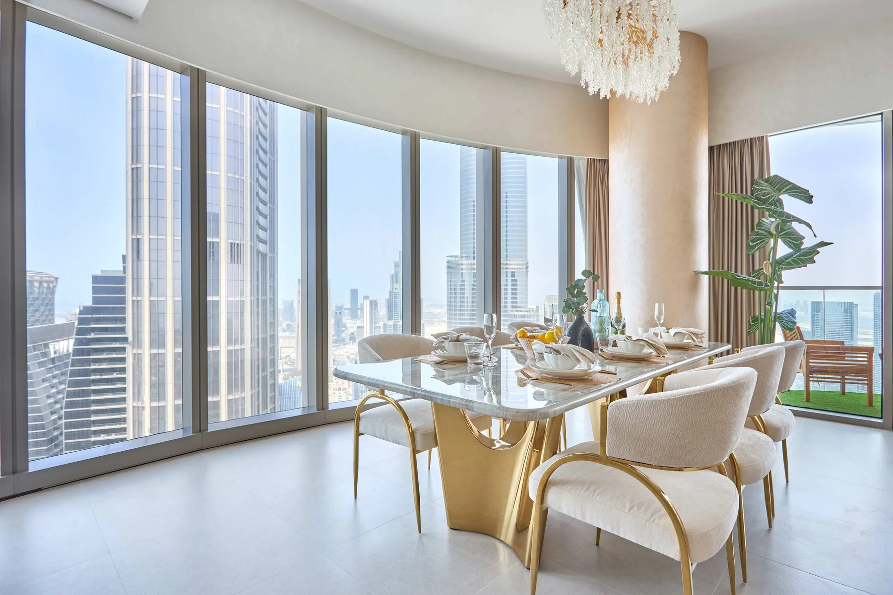 Comedor con la mesa puesta junto a ventanales con vistas a la ciudad.