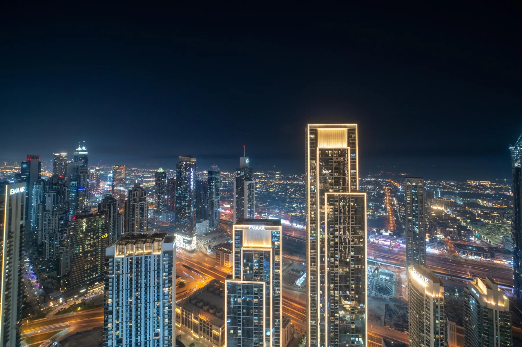Un horizonte urbano nocturno con edificios altos iluminados y carreteras.