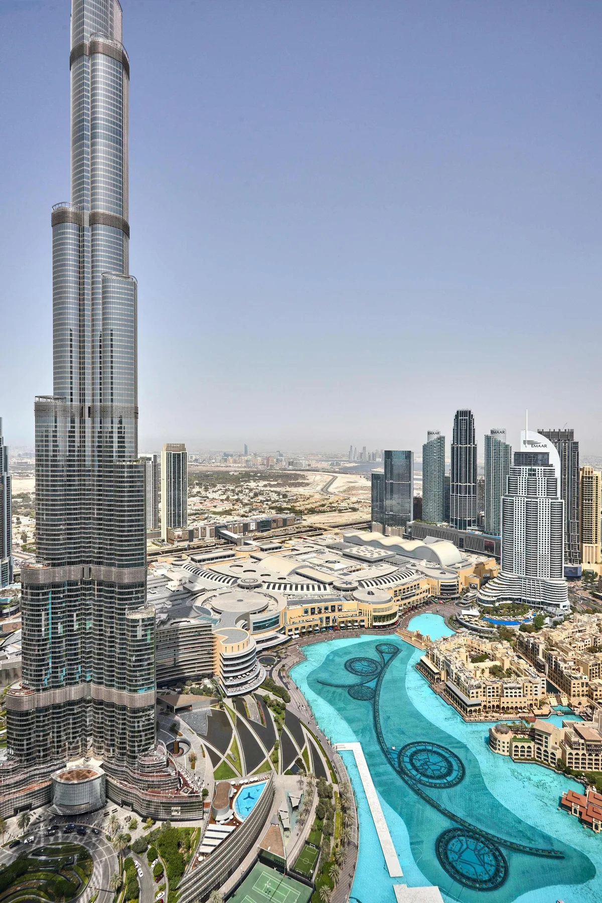 Un perfil urbano se alza sobre una gran piscina turquesa y edificios circundantes.