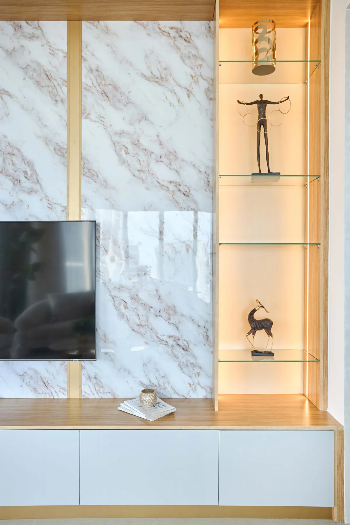 Una pared multimedia de sala con televisor junto a estantes iluminados de exhibición.