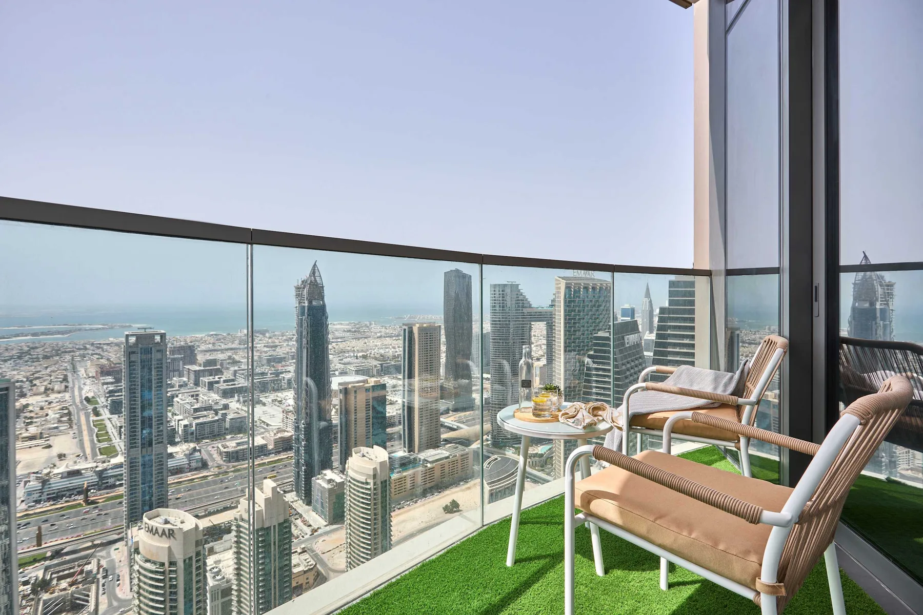 Una zona de estar en un balcón elevado ofrece vistas a un denso perfil urbano.