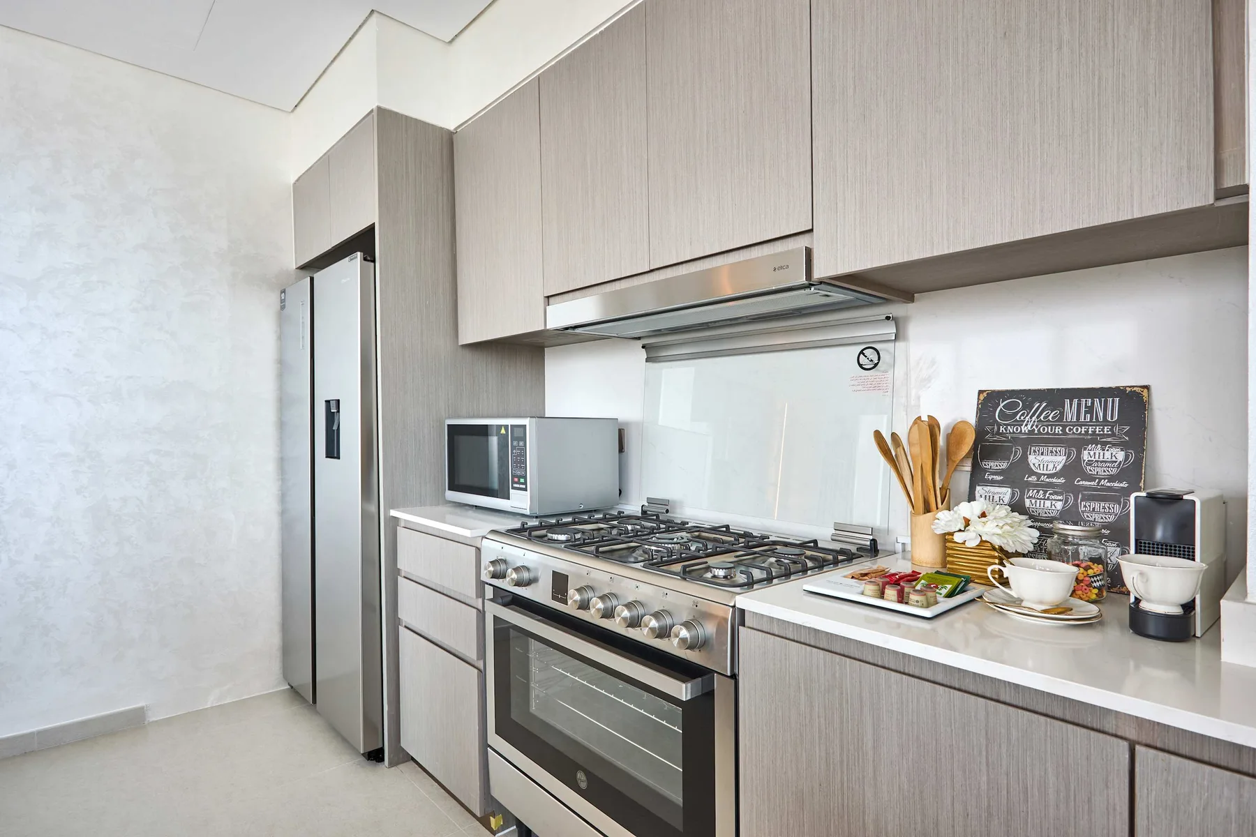 Una cocina moderna con una estufa de acero inoxidable y gabinetes de madera clara.