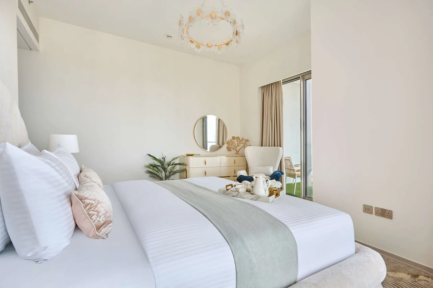 Un dormitorio luminoso con una cama tendida y una cómoda junto a la ventana.