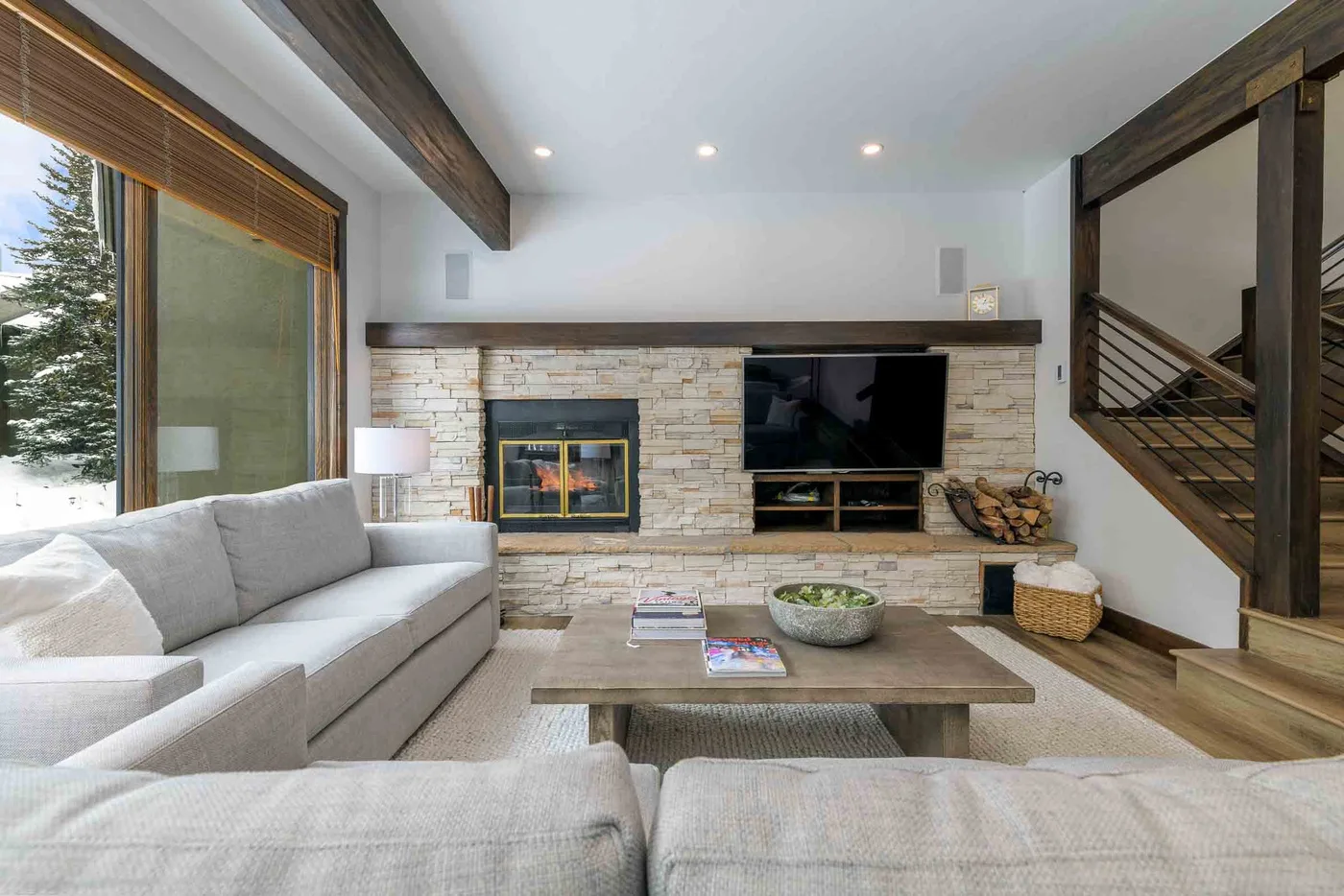 A bright living room with a stone fireplace and television.