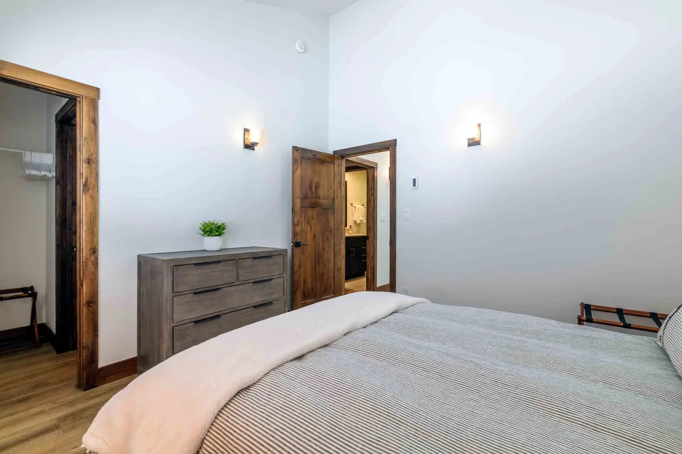 A bedroom with a bed, wooden dresser, and open doorway.