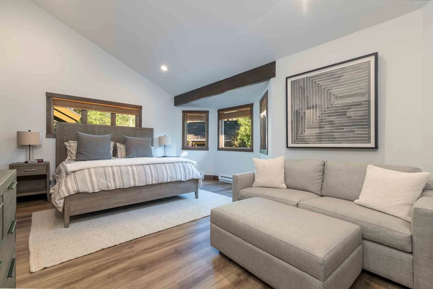 A bedroom with a bed and a light-colored seating area.