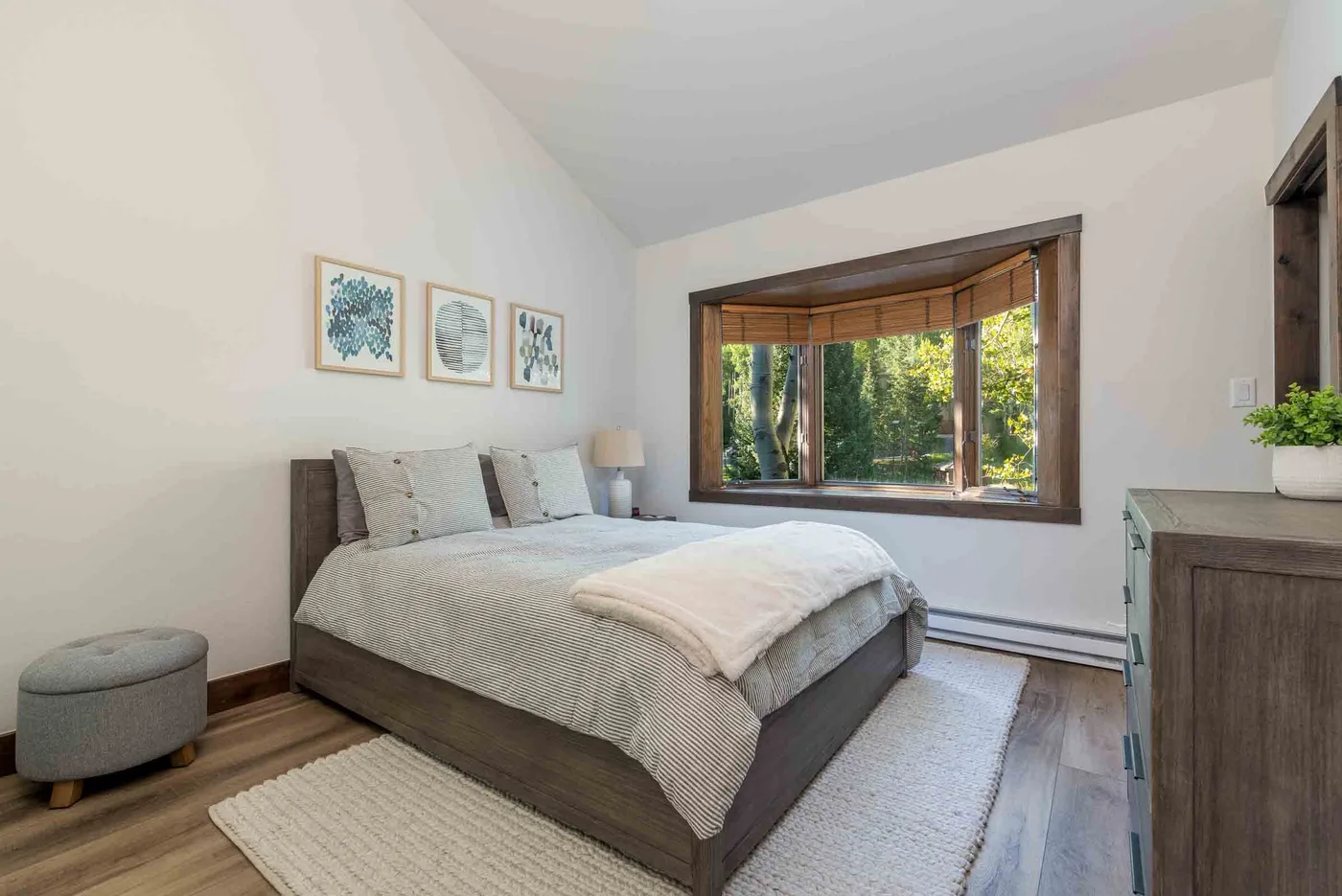 A bright bedroom with a neatly made bed beside a large window.