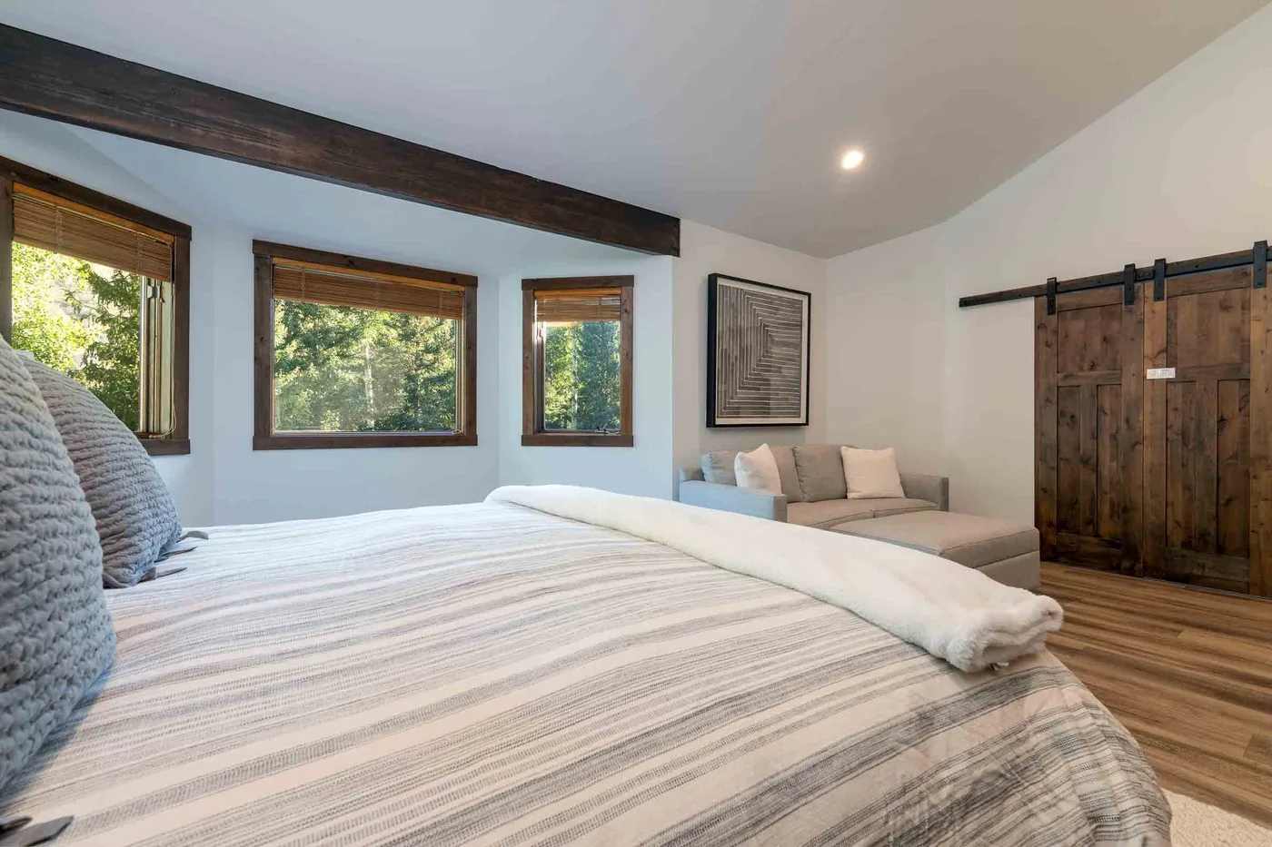 A bedroom with a large bed, windows, and a small seating area.