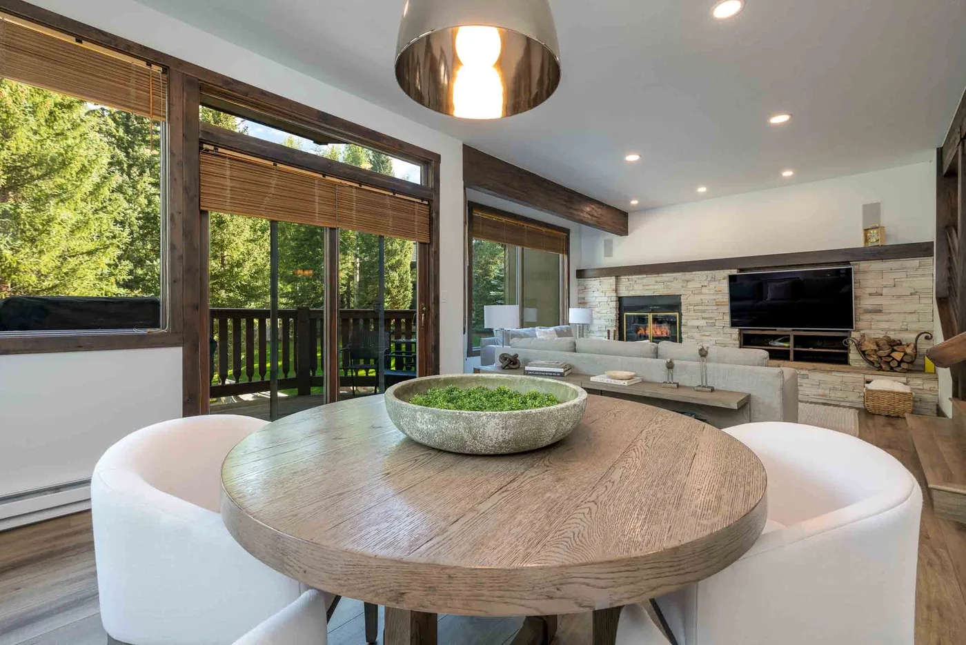 A bright living room with a round dining table and seating beside large windows.