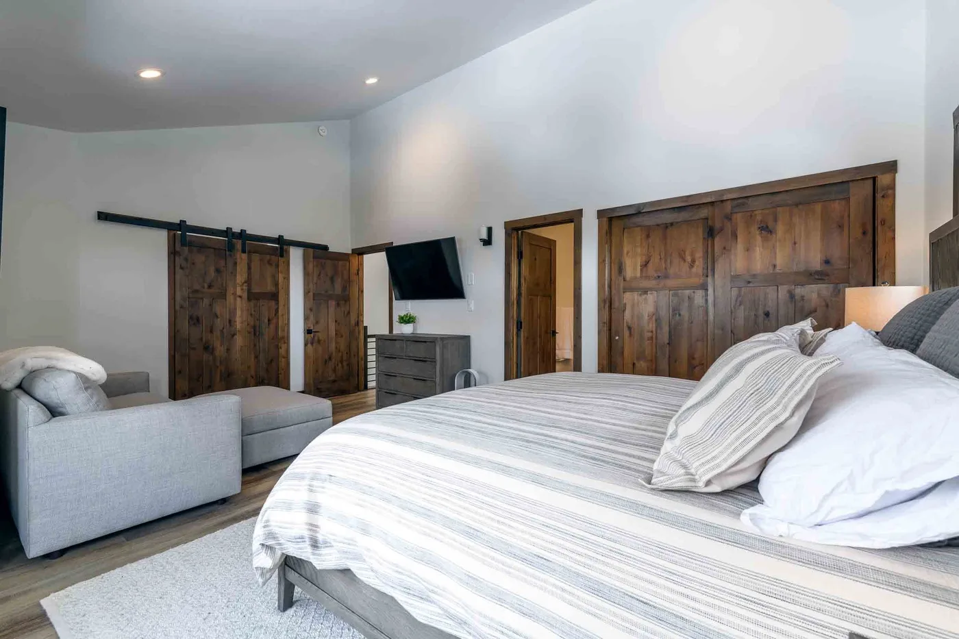 A bedroom with a striped bedspread and dark wooden doors.