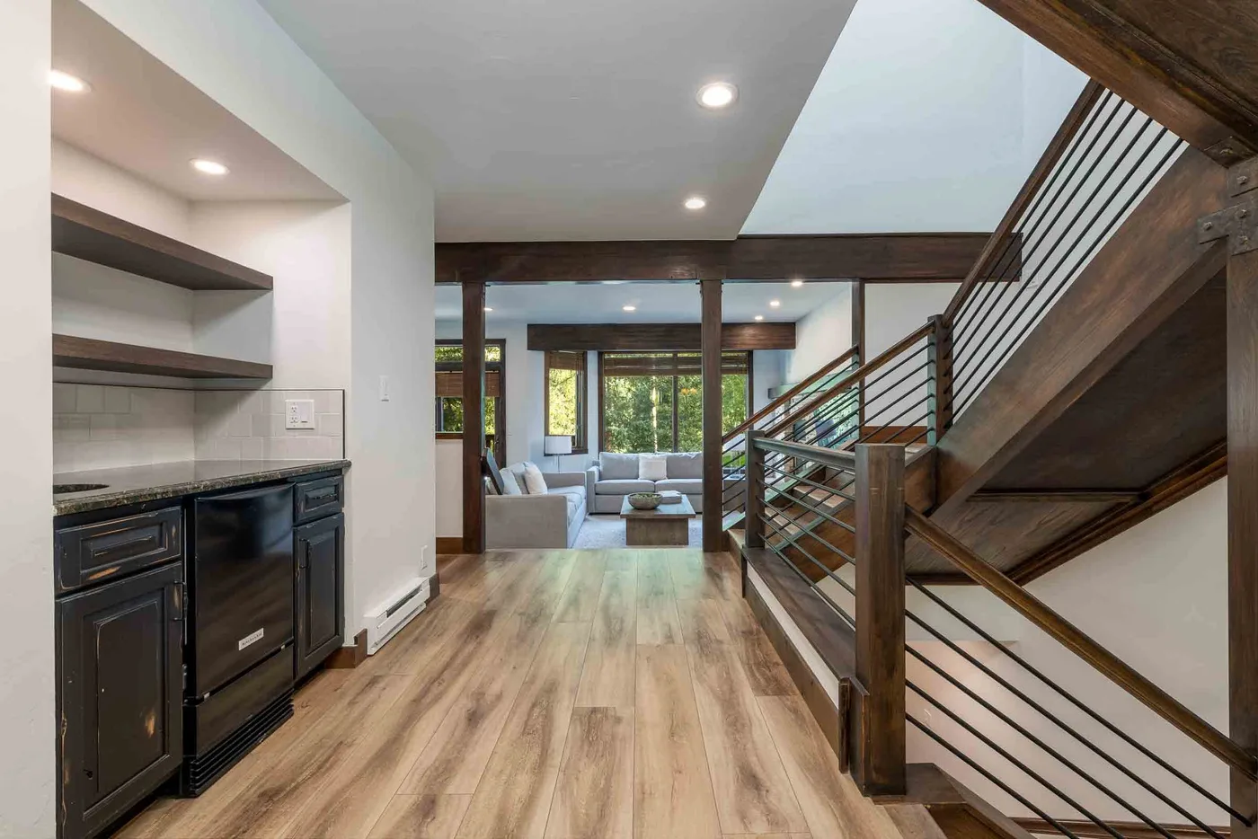 A modern open-plan interior with a kitchenette, living area, and staircase.