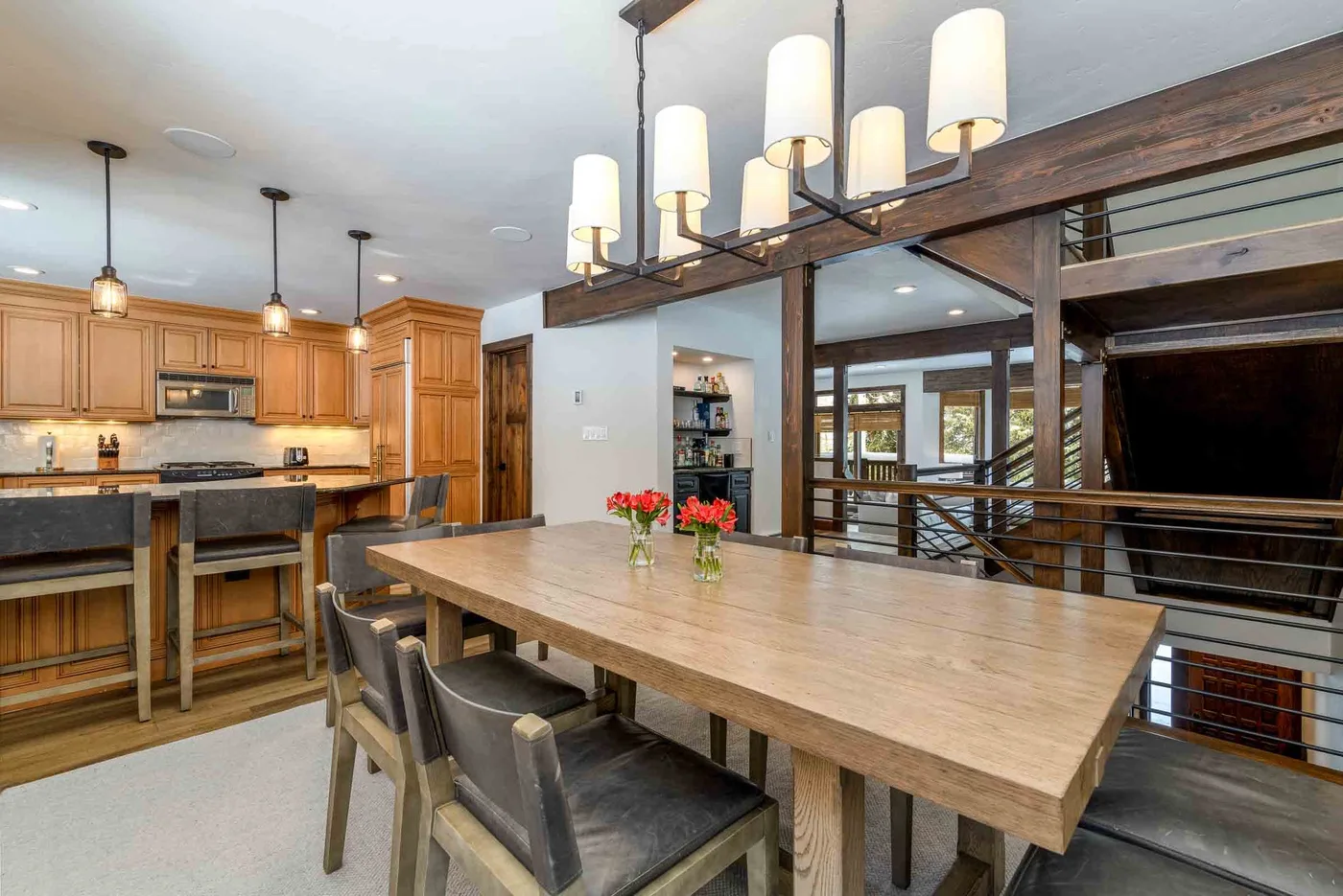 A dining area with a long wooden table beside an open kitchen.
