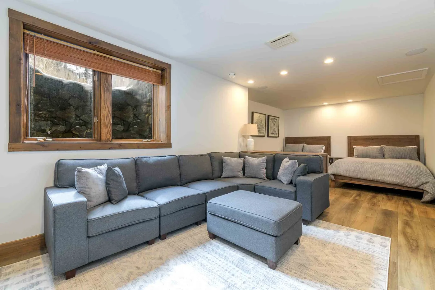 A living area with gray seating and a bed in the background.