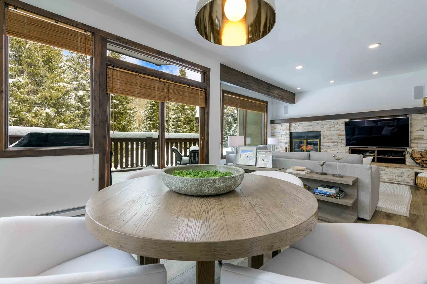 A bright living room with a round dining table and seating beside large windows.