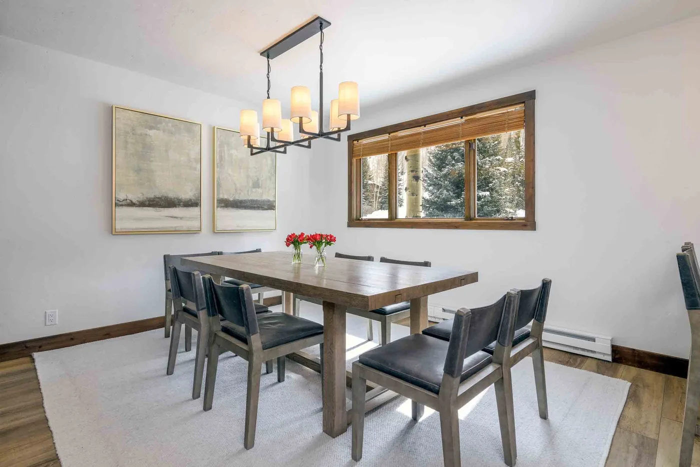 A dining area with a wooden table and chairs beneath a hanging light.